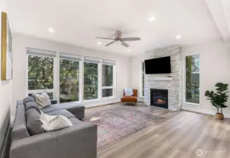 Living area with expansive windows bringing in natural light and wooded surroundings.