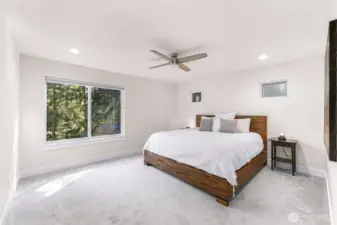 Spacious primary bedroom with large window and ceiling fan