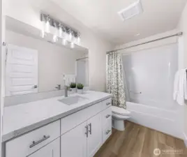 Full bathroom with quartz-style countertop, single vanity, and tub/shower combo