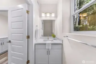 Half Bath near laundry and garage with quartz countertop, shaker-style cabinetry, and natural light from nearby window.