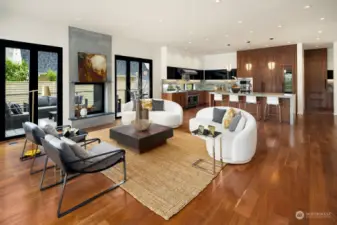 The open living room flows into the luxe kitchen and dining room, all connected with ever-present natural light and consistent aesthetic. Note also the seamless indoor-outdoor flow via accordion door system – extending the living area, leading to an atrium lounge and kitchen space, replete with Wolfe BBQ kitchen station.