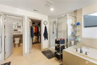 Floating shelves and plank siding in primary with walk in closet that has additional custom racks adding more hanging area for clothes.