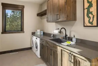 Huge utility room just off the 2 car garage, with sink and custom cabinets provides ample counterspace and bar for hanging clothes. Laundry chute delivers convenient connection to upstairs.