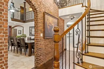 Beautiful Curved Staircase with Tasteful Wrought Iron & Solid Wood Hand Railing extends along the entire upper floor.