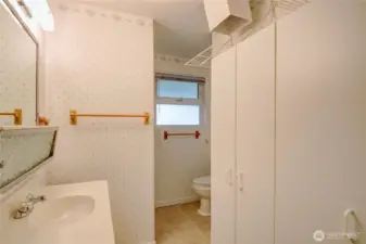 Lower level 3/4 bath with storrage cabinets and laundry shoot from the primary bedroom upstairs.