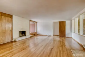 Living Room showcasing the original hardwood floor. These windows provide an abundance of natural light and makes this room happy and bright, even on gloomy Seattle days. Doorway at the far end leads to the hallway, 2 bedrooms, and the full bath.