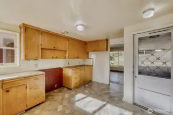 View 1 of the kitchen. This room needs a lot of love, with original cabinets and butcher block countertops still here. The appliances have been removed, but the dishwasher is still in place. New sheet vinyl flooring was installed in January 2026. Bring your imagination and ideas, and make this kitchen a showpiece where friends want to gather.