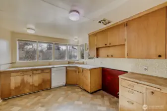 Kitchen View 2. Great territorial views from all these windows! Original light fixtures, too! There's even a passthrough window from the kitchen to the deck to make al fresco dining a piece of cake! Bring your ideas and make this kitchen beautiful again.