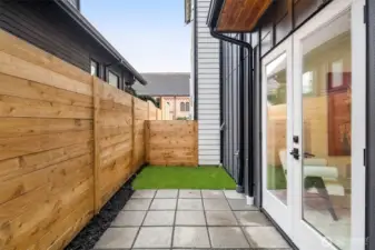 Secluded outdoor living area with a modern horizontal wood fence, stone pavers, and low-maintenance turf.
