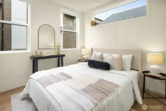 Bright and inviting guest suite or secondary bedroom with large windows and a clean, modern aesthetic.