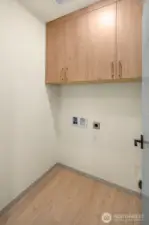 Functional utility room equipped with overhead storage cabinetry and dedicated hookups for a washer and dryer.