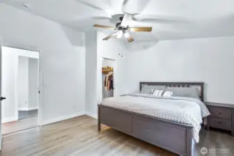 Spacious primary bedroom with ceiling fan, walk-in closet, and durable laminate flooring.