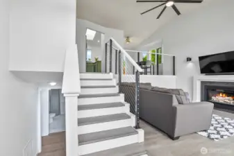 Split-level layout with open railing, modern ceiling fan, and easy flow from living to kitchen and dining areas.