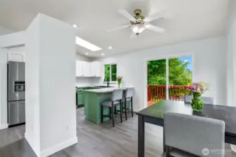 Open dining area with slider to back deck. Seamless flow into kitchen with bar seating, updated lighting, and LVP flooring.