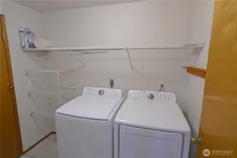 Dedicated laundry room with full-size washer and dryer plus built-in shelving for extra storage and organization.