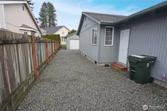 Side of the property shows the door to the garage, siding in good condition and the detached garage workshop. Access to the detached garage is wide enough for a car or RV. Past owner used it to store her RV.