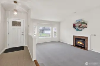 Entryway and living room with a lot of light and gas fireplace.