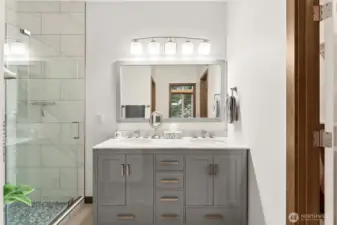 Fully updated primary bathroom featuring a tiled shower surround, glass enclosure, and new fixtures.