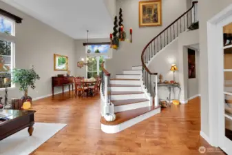 Grand foyer with curving staircase, vaulted ceilings, skylights, and hardwood floors.