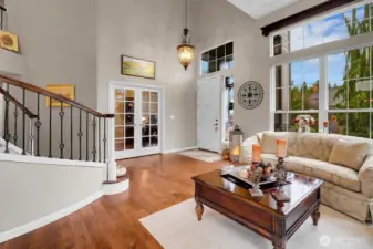 Grand foyer/formal living room with curving staircase, vaulted ceilings, skylights, and hardwood floors.