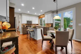 Open concept kitchen with granite counters, white cabinets, hardwood floors, and backyard access.