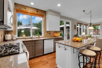 Open concept kitchen with granite counters, white cabinets, hardwood floors, and backyard access.
