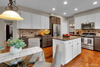 Open concept kitchen with granite counters, white cabinets, hardwood floors, and backyard access.