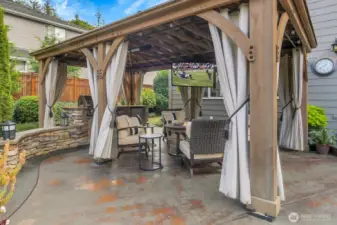Outside living at it's best! Gazebo, stone island with grill and fridge, heaters, and TV included!