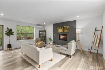 Windows flood the living area with light, showcasing the surrounding trees and forest.