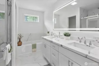 Spa like bathroom in the primary bedroom, with custom tile, quartz counters and LED mirror.