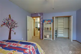 Kids room with a large built-in closet organizer featuring plenty of shelving