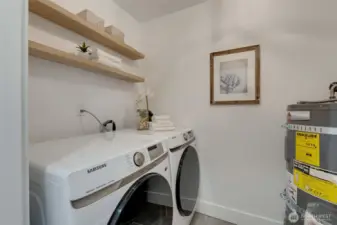 In Unit Laundry room with brand new Washer and Dryer as well as floating shelving and wash basin.