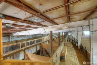 View looking at main barn stalls & spectator bleacher/arena from upper deck area.
