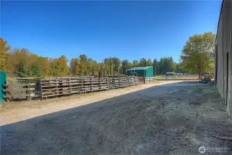 View of the back arena alley, cattle pens beyond and shavings bin - directly across the track you will find paddocks