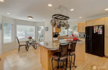 Airy Kitchen features maple floors and cabinets, granite counters, prep island, pan rack, and more!