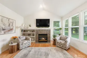 Open living room with vaulted ceilings, a gas fireplace, and plenty of natural light.