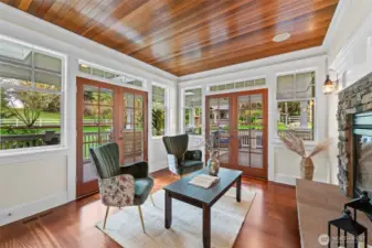 An intimate sanctuary featuring one of the home's four fireplaces and a rich, wood-planked ceiling. French doors open directly to the wrap-around veranda, perfect for transitioning from a quiet afternoon read to evening air.