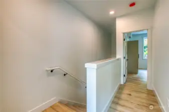 The hallway connects two upstairs ensuite bedrooms, with a laundry area conveniently located at the top of the stairwell.