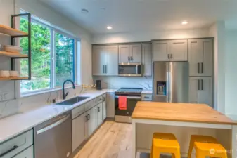 The kitchen features sleek quartz countertops and a central island topped with a butcher block surface, perfect for casual dining.