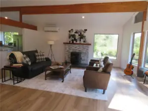 Living room with vaulted ceilings and wooden beams throughout this area including kitchen and dining area. Pellet stove shown here.