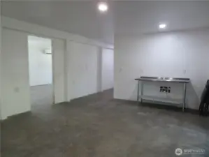 Larger bedroom in lower level, dining area, ktichen against the wall with hookups for stove, refrigerator and sinks.  Middle hallways takes you to the laundry room and the .75 bath space with all of the hookups of laundry and bathroom.