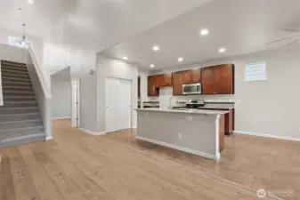 This view shows how well the main floor flows. From the family room, you can see straight into the kitchen, down the hallway to the powder room, and back toward the dining room, which makes the whole space feel connected and intuitive. The staircase and two story entry add visual interest, highlighted by another new light fixture overhead. Even the recessed lighting has been upgraded to LEDs, because yes, details matter. The kitchen island pulls double duty with seating and three built-in outlets, perfect for laptops, homework, or charging everything all at once.