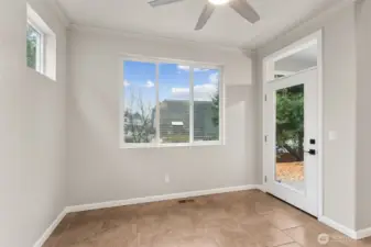 A glass door with an overhead accent window opens straight to the covered back patio, which makes grilling and outdoor dining feel effortless. Tile floors are exactly what you want at an indoor outdoor transition point, durable and easy to clean. Contemporary black door hardware adds contrast, while rounded wall corners and crown molding painted to match the walls keep the look soft and understated. It’s casual, intentional, and surprisingly elevated.