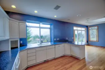 Oriented towards the view, well planned kitchen with white cabinetry, granite countertops, breakfast nook, double oven, appliance garage, and gleaming wood floors.