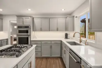 Kitchen features under-cabinet lighting, island with gas range plus down draft, slab quartz counters with under-mount stainless trough sink.