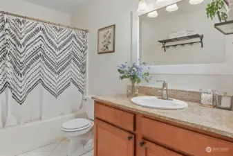 Full bathroom with light neutral colors, nice cabinets, stone countertop.