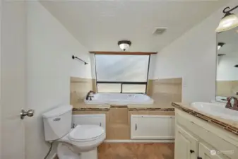 This bathroom is located on the main level of the home. It has a jetted tub and a large window that lets in lots of natural light.