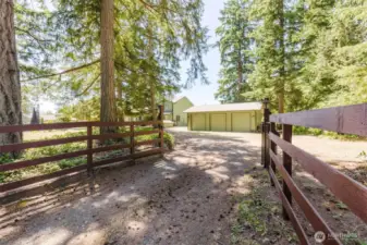 Welcome home!  As you enter through the gate, you will the 3 car garage with 9ft doors.  House to the left and the road down to the shop to the right.