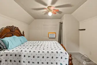 Upstairs bedroom with additional wall ac unit and ceiling fan.