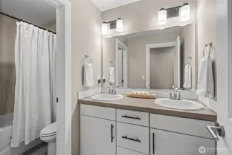 With spa-like features, this shared bathroom located on the upper floor features a dual vanity and floor to ceiling tiling in the shower.